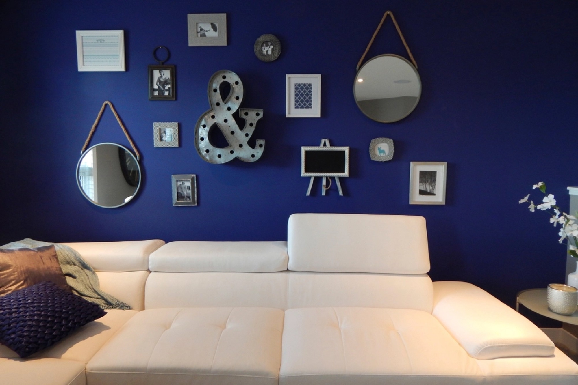 A deep navy accent wall with framed art above a white sofa.