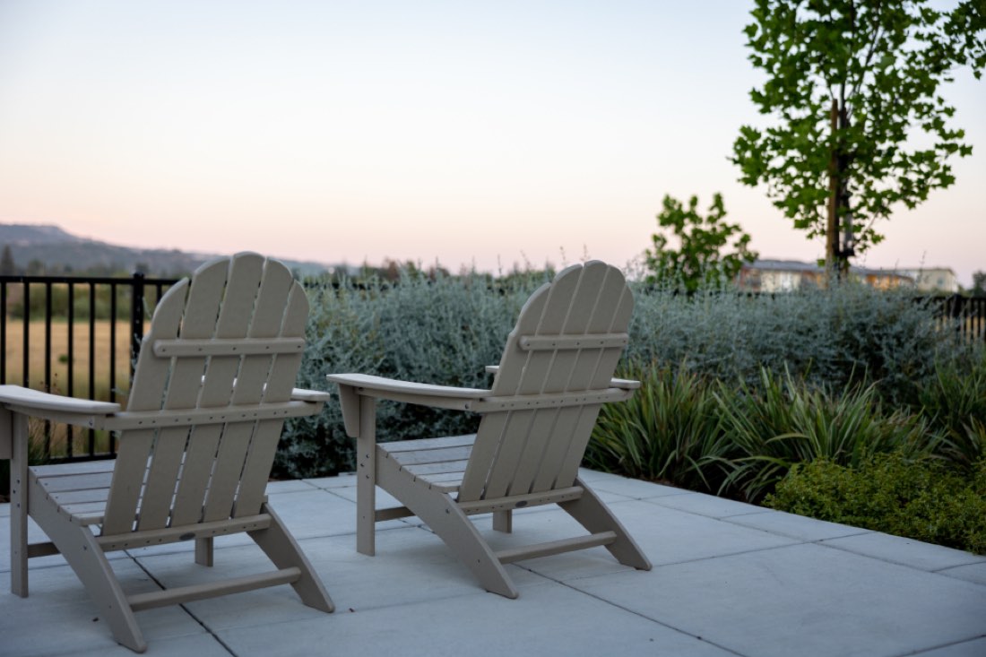 Two chairs on a stone terrace at dusk, facing an open landscape.
