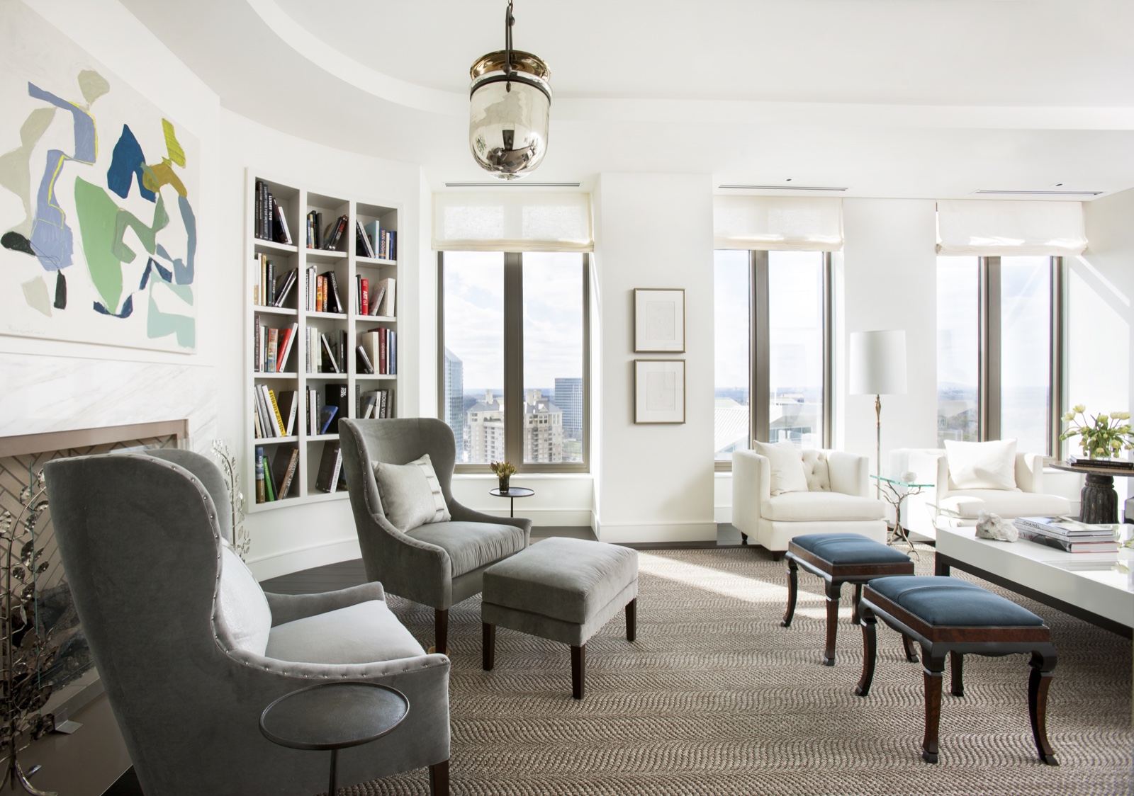 An elegant white living room with a built-in bookcase and tall windows.